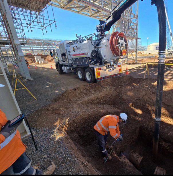 Vac truck potholing beside an open excavation